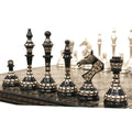 Soviet-inspired brass metal chess pieces in profile view on a luxury art board.