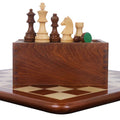 Tournament chess set pieces lined up on a wooden storage box over an inlaid wood board.
