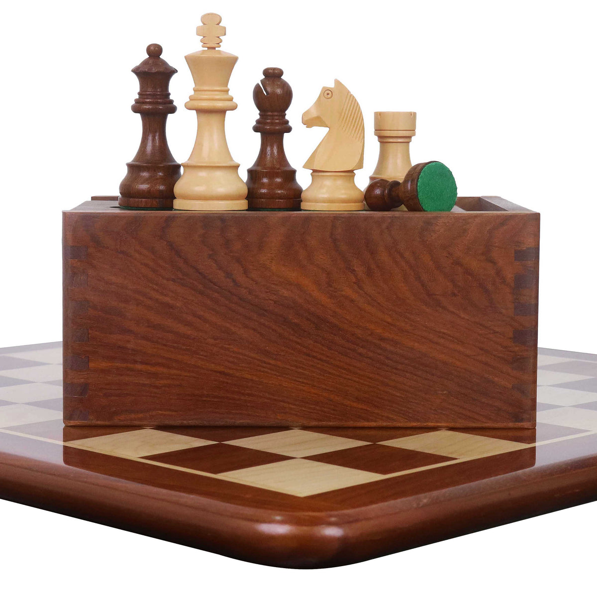 Tournament chess set pieces lined up on a wooden storage box over an inlaid wood board.