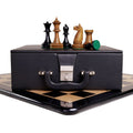 Antiqued boxwood chess pieces displayed on a premium leatherette storage coffer.