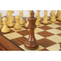 Dark wood Staunton king chess piece standing on a wooden board.