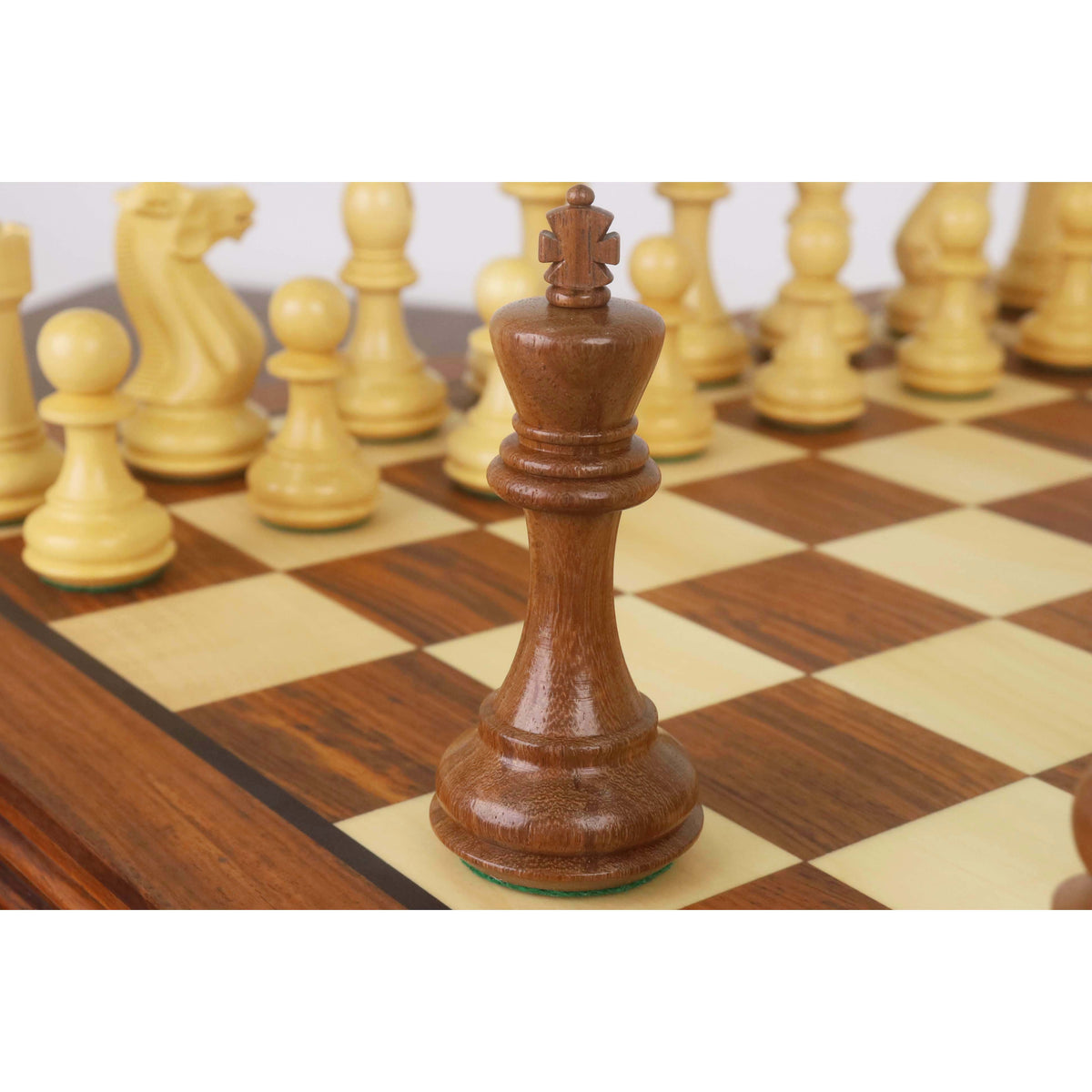 Dark wood Staunton king chess piece standing on a wooden board.