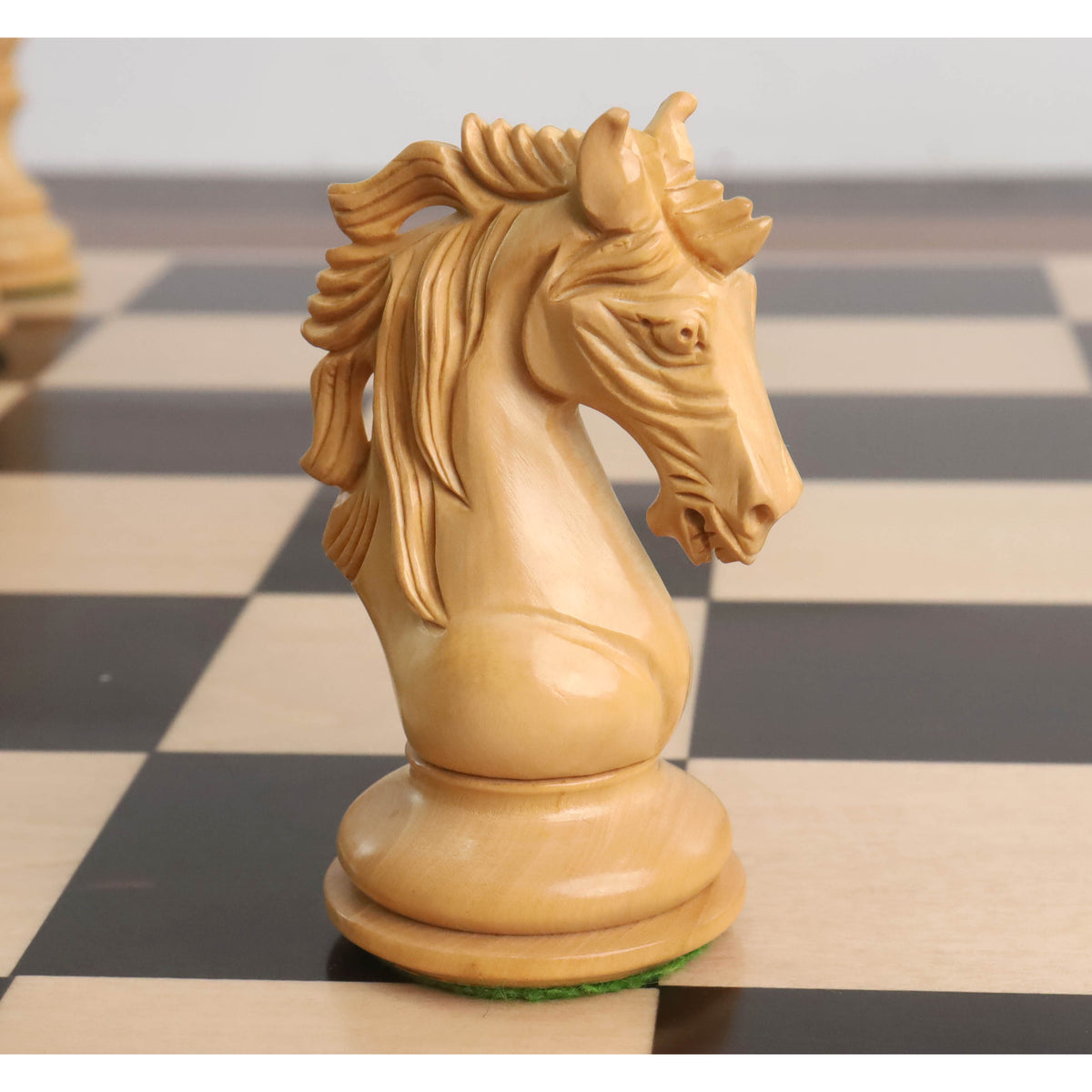A detailed close-up of the handcrafted Boxwood Knight from the Goliath Series Staunton chess set, standing on a chessboard square.
