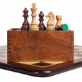 Rosewood and boxwood tournament chess pieces displayed on a matching wooden slide top storage box.