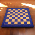 Full perspective view of the 22" Blue Ash Burl chess board with 57mm squares on a wooden surface.