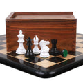 White and black Pro Staunton chess pieces standing in front of a golden rosewood storage box on an ebony board.