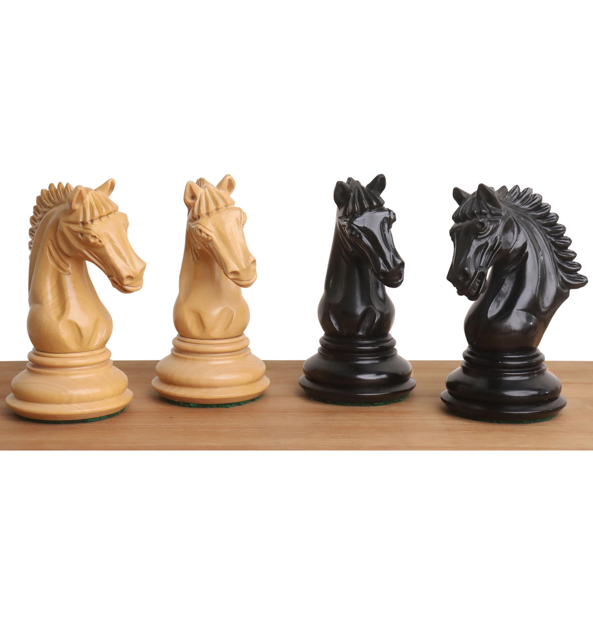 Detailed close-up of handcrafted ebony and boxwood Tilted Knight chess pieces.