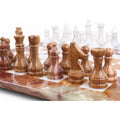 Close-up of brown onyx marble chess pieces with natural veining on a matching stone chessboard.