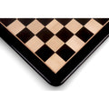 Close-up view of the corner of a 23 inch ebony and maple wood chess board showing the rounded edges and fine inlay work.