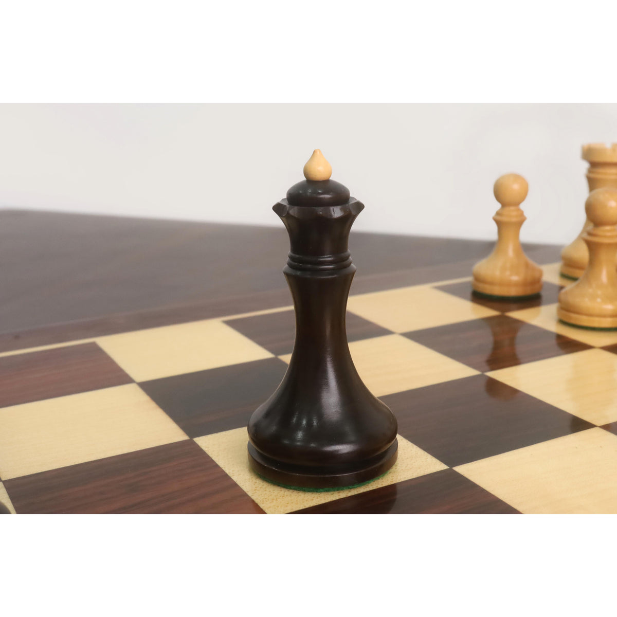 Mahogany stained boxwood Queen of the 3.8" Candidates Series Minimalist chess set positioned on a wooden board.