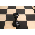 Single black Goliath Series Staunton Rook chess piece on a wooden board square.
