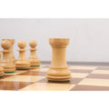 Boxwood Staunton rook with a weighted chamfered base standing on a wooden chessboard.