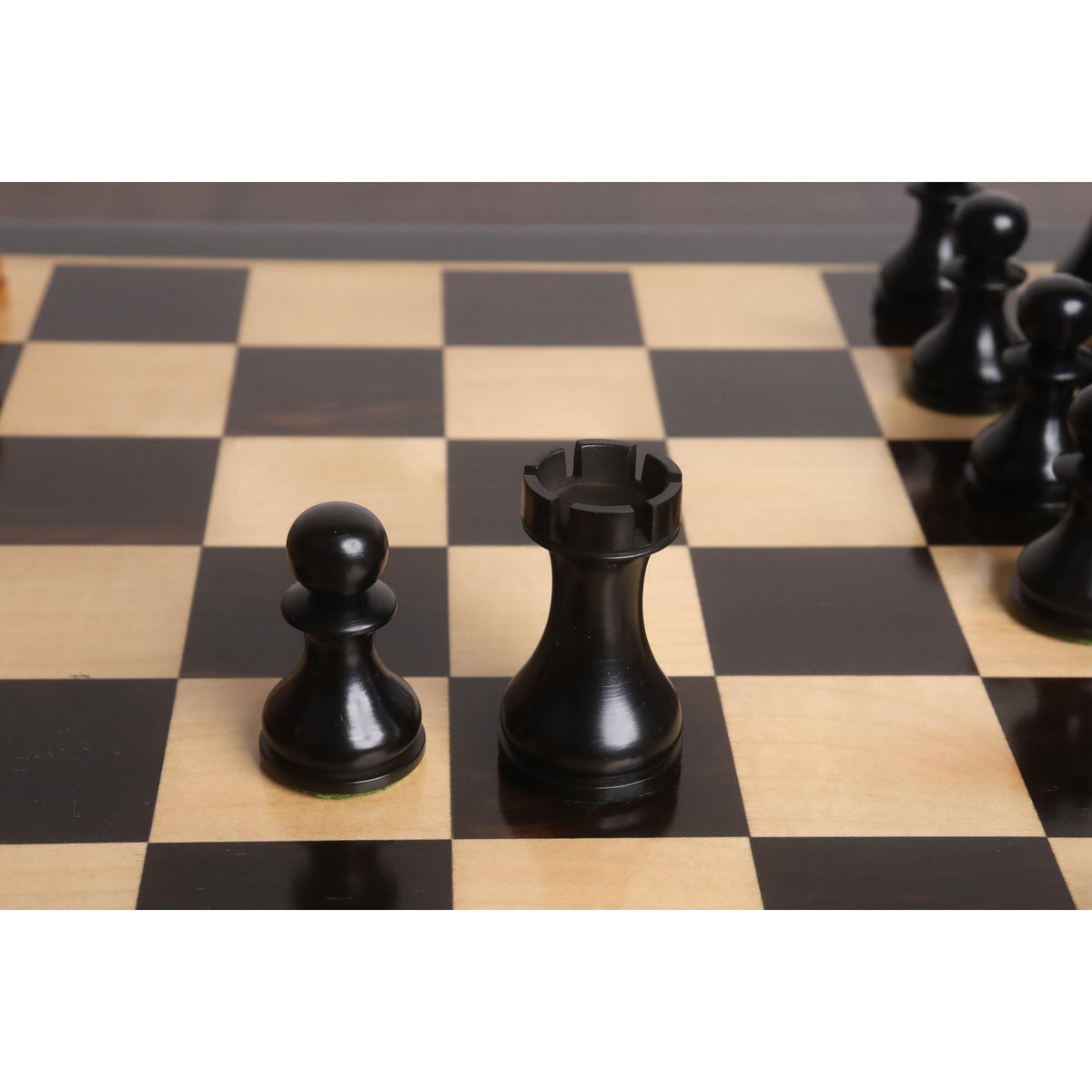 Close-up of black ebonised pawn and rook from the 3.6" English Dublin chess set on a wooden board.