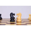 Close-up of ebonised boxwood and boxwood knight chess pieces on a magnetic travel chess board.