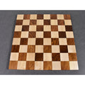 Empty golden rosewood and maple chess board showing the 64 squares against a grey background.