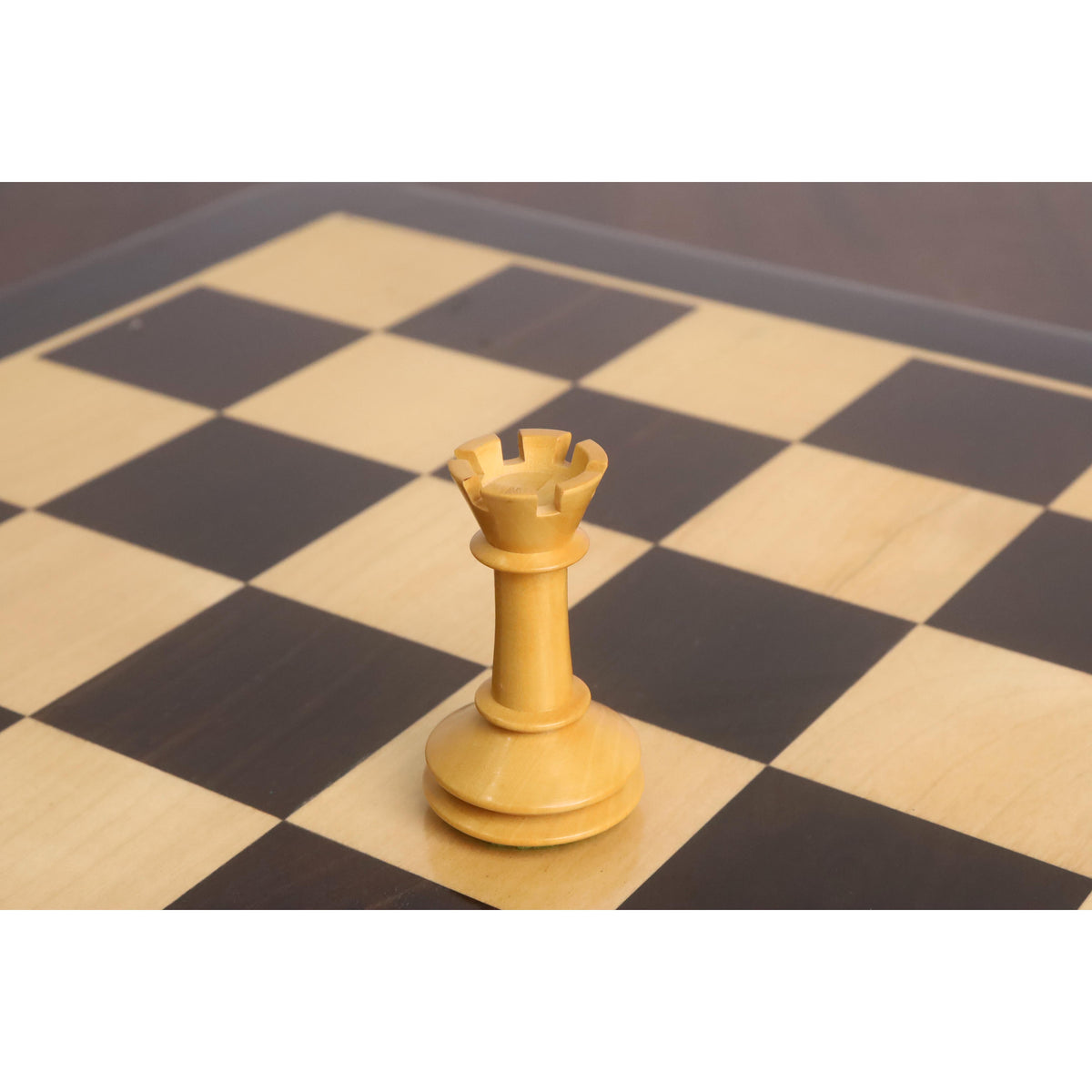 White boxwood rook from the 3.5" Monolith miniature chess set standing on a wooden chessboard.