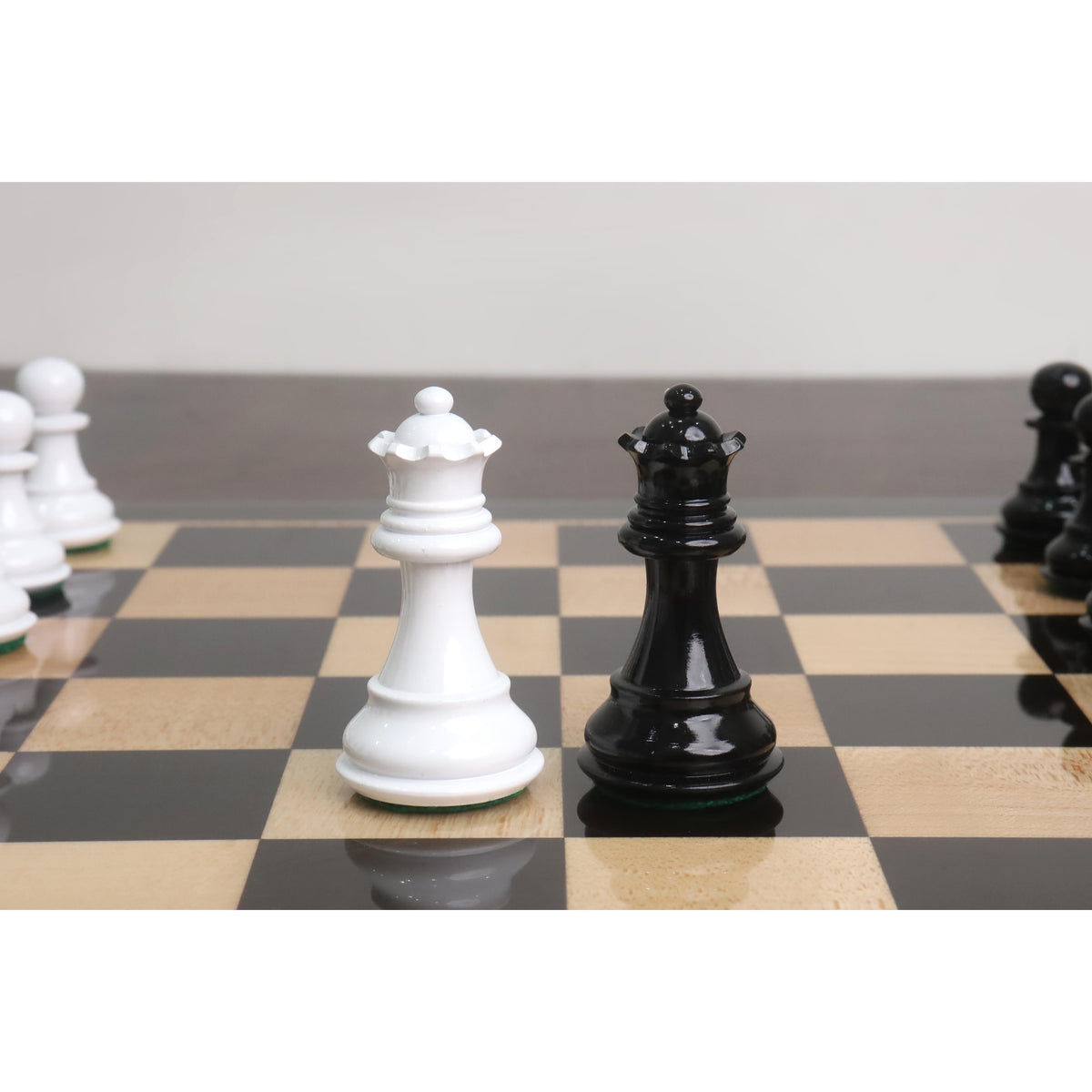 White and black Pro Staunton wooden chess queens showcased on a glossy ebony and maple board.