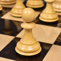 Detailed view of a boxwood pawn from the luxury Sleek Staunton chess set resting on a glossy dark square.