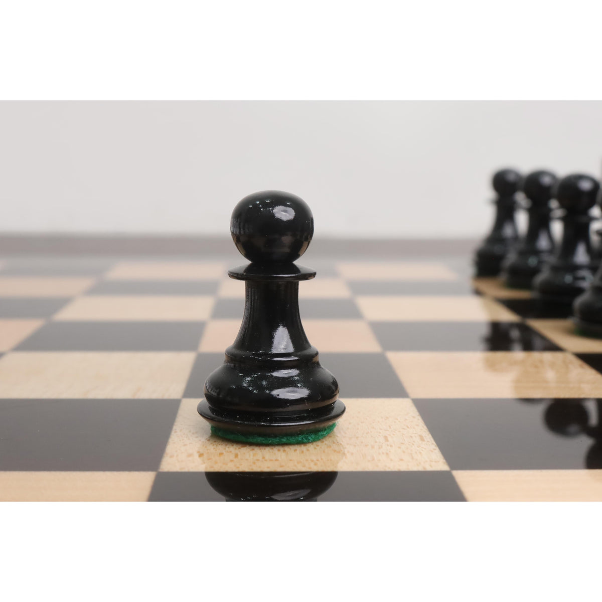 Detailed view of a glossy black Pro Staunton wooden pawn piece on a handcrafted ebony board.