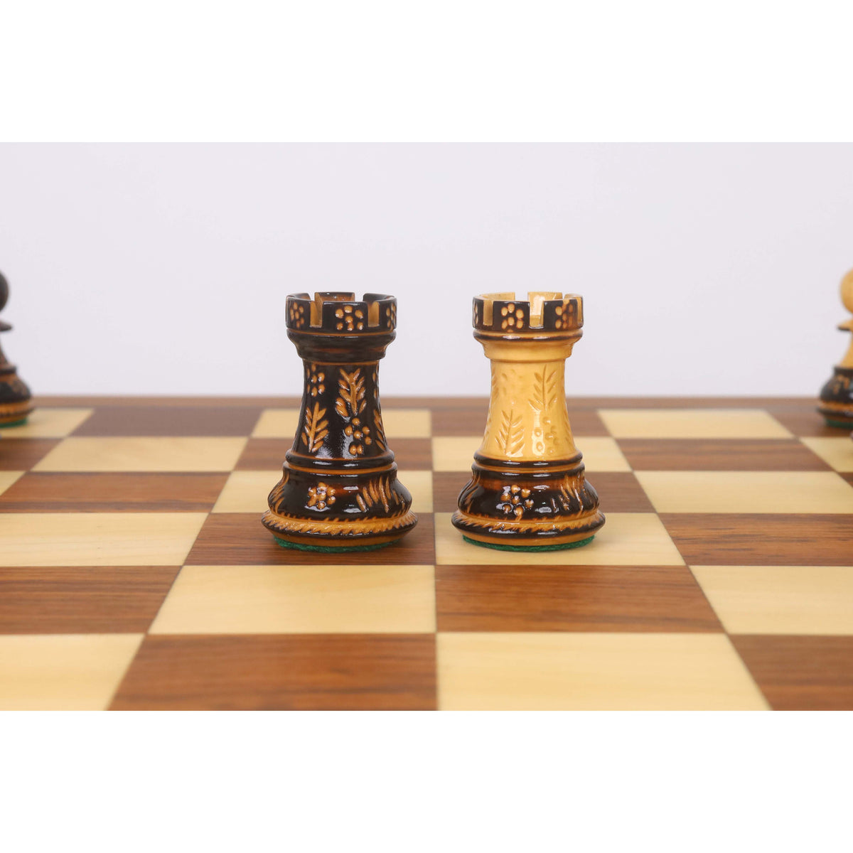 A side-by-side view of a dark and a light golden rosewood Staunton rook on a 20-inch legacy chess board.