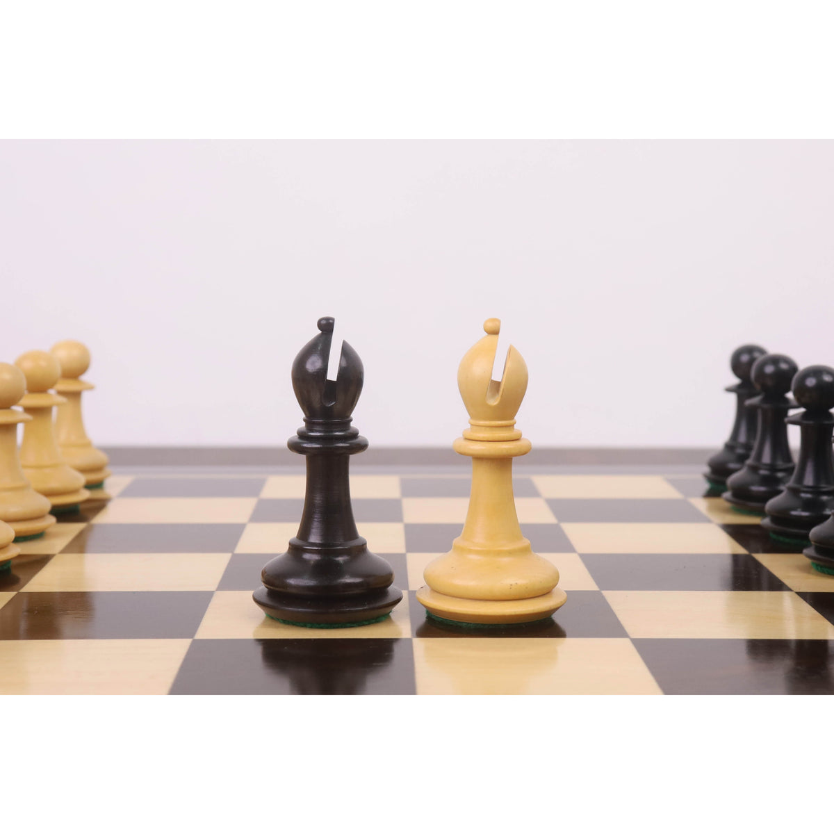 The light and dark wood Bishop pieces from the 3.9" Heritage Series Staunton chess set are positioned centrally on a chessboard.