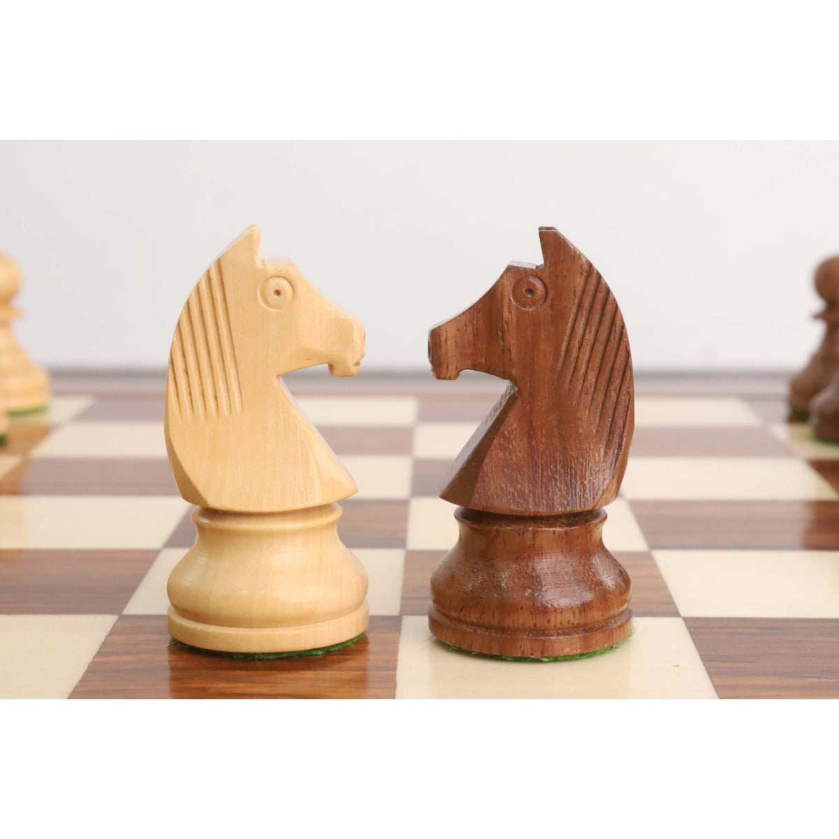 Golden rosewood and boxwood knights facing each other on a handcrafted wooden chess board.