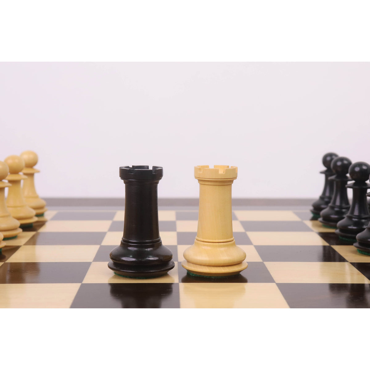 The light and dark wood Rook pieces from the 3.9" Heritage Series Staunton chess set are positioned centrally on a chessboard.