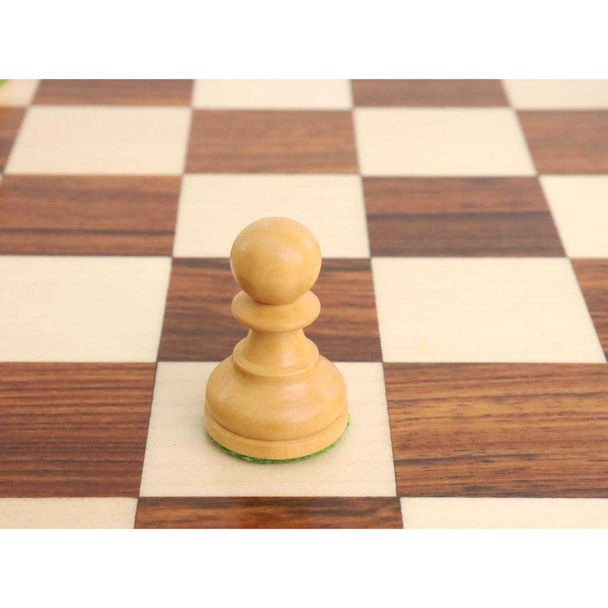 Close-up of a natural boxwood pawn from the tournament Staunton set sitting on a wooden board.