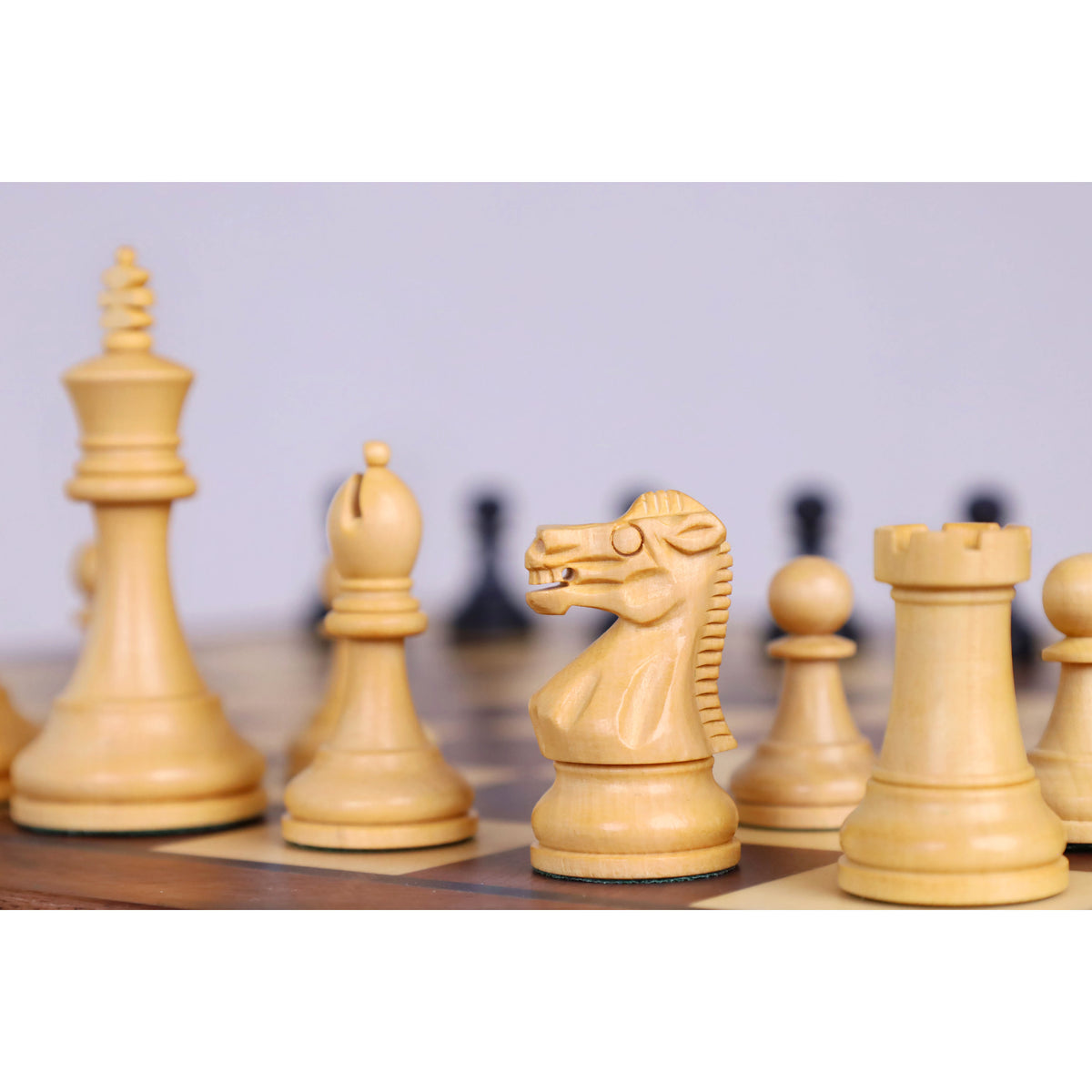 Boxwood Staunton chess pieces lined up on a magnetic travel chess board.