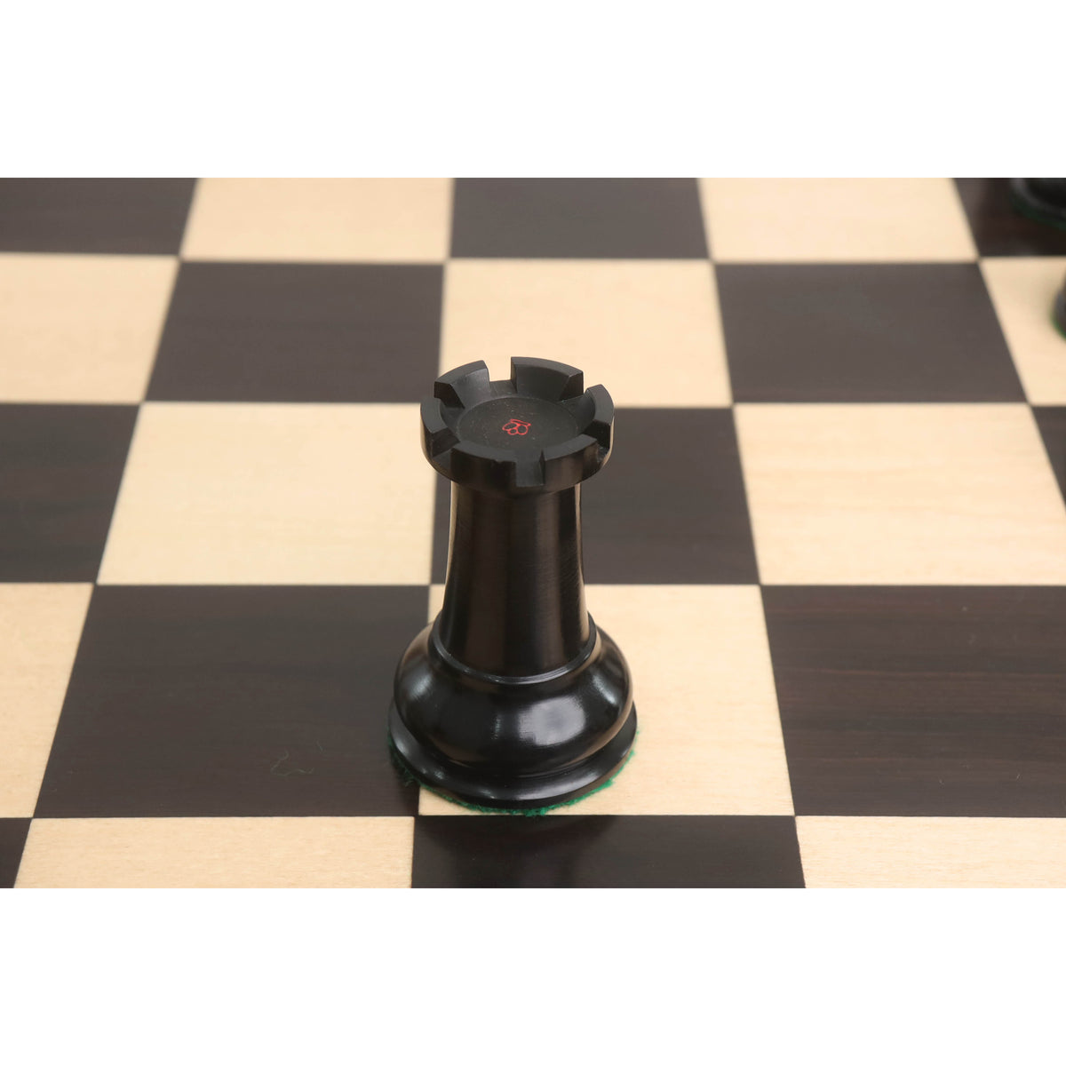 Ebony rook from the 1849 Cooke Staunton set featuring a red crown stamp on a wooden board.