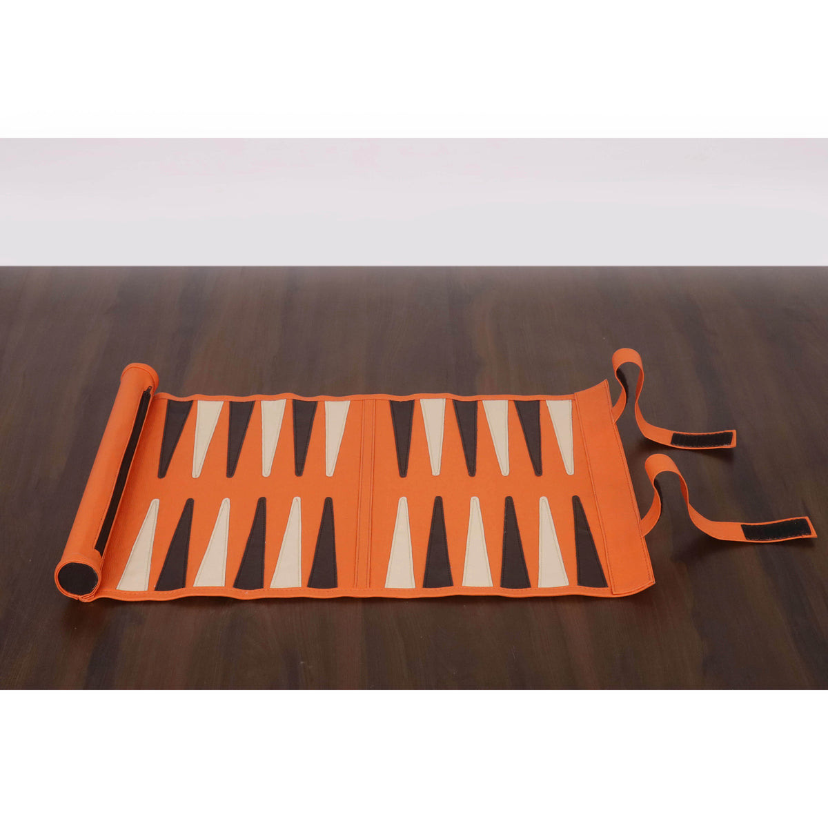 Handcrafted roll-up backgammon board in orange finish displayed on a dark table.
