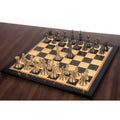 High-angle view of the luxury brass metal chess set in metallic gold and grey fully set up on a wooden chessboard.