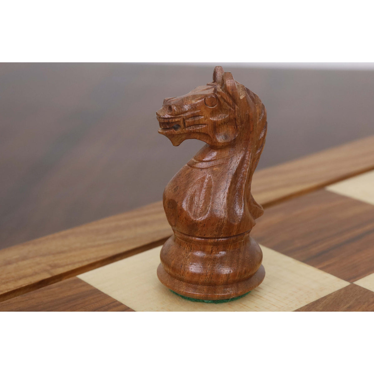 Close-up of a carved golden rosewood knight chess piece on a luxury board.