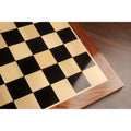 High-angle shot showing the smooth matte finish and grain of the Golden Rosewood border on an Ebony and Maple chessboard.