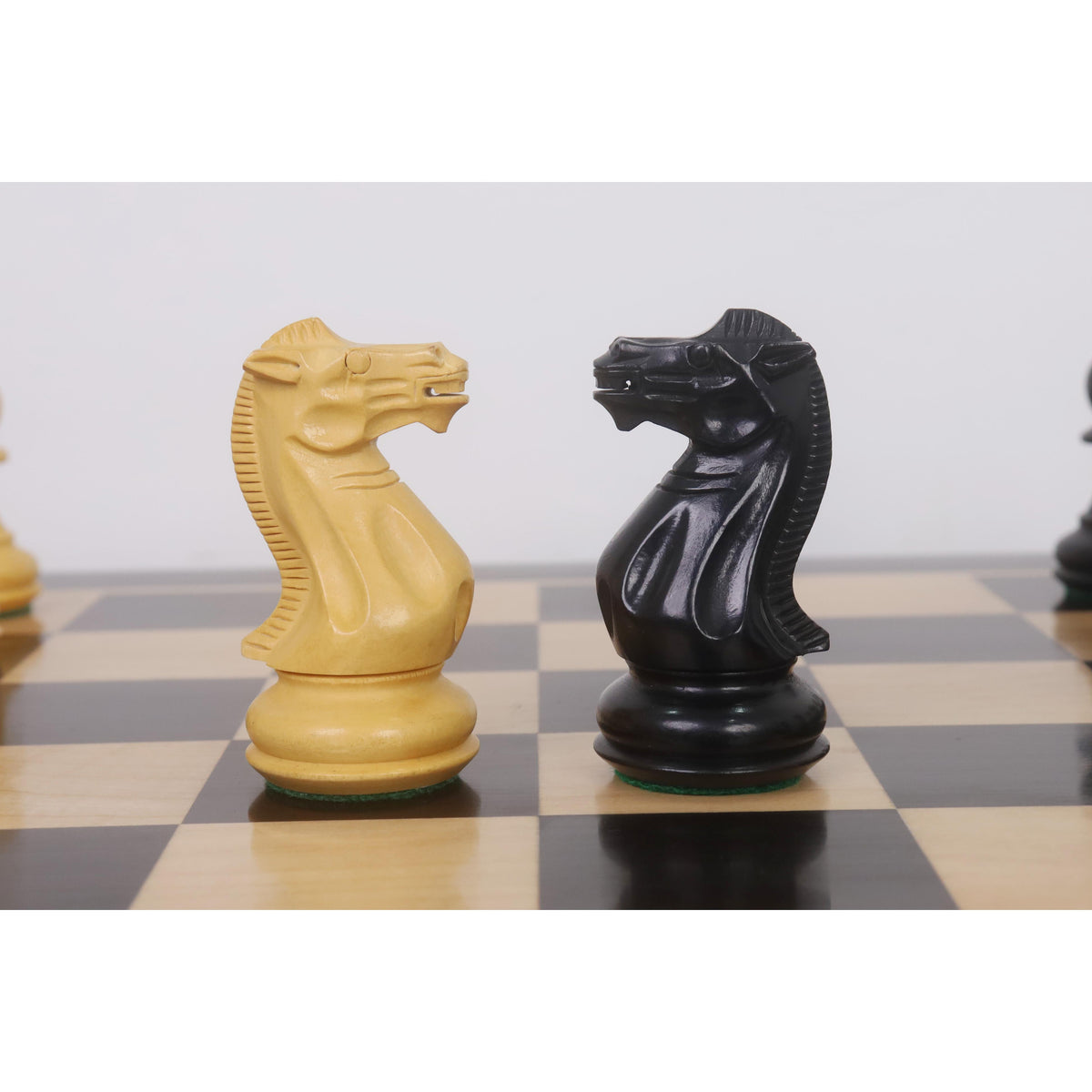 Face-off between Ebonised and Boxwood Pro Staunton Knights on a chessboard.