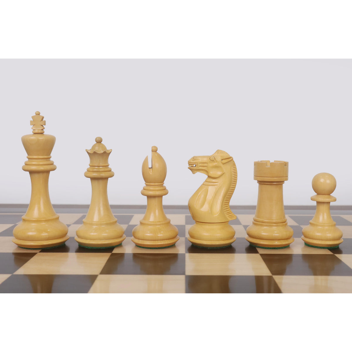 Boxwood Pro Staunton chess pieces lined up on the wooden board.