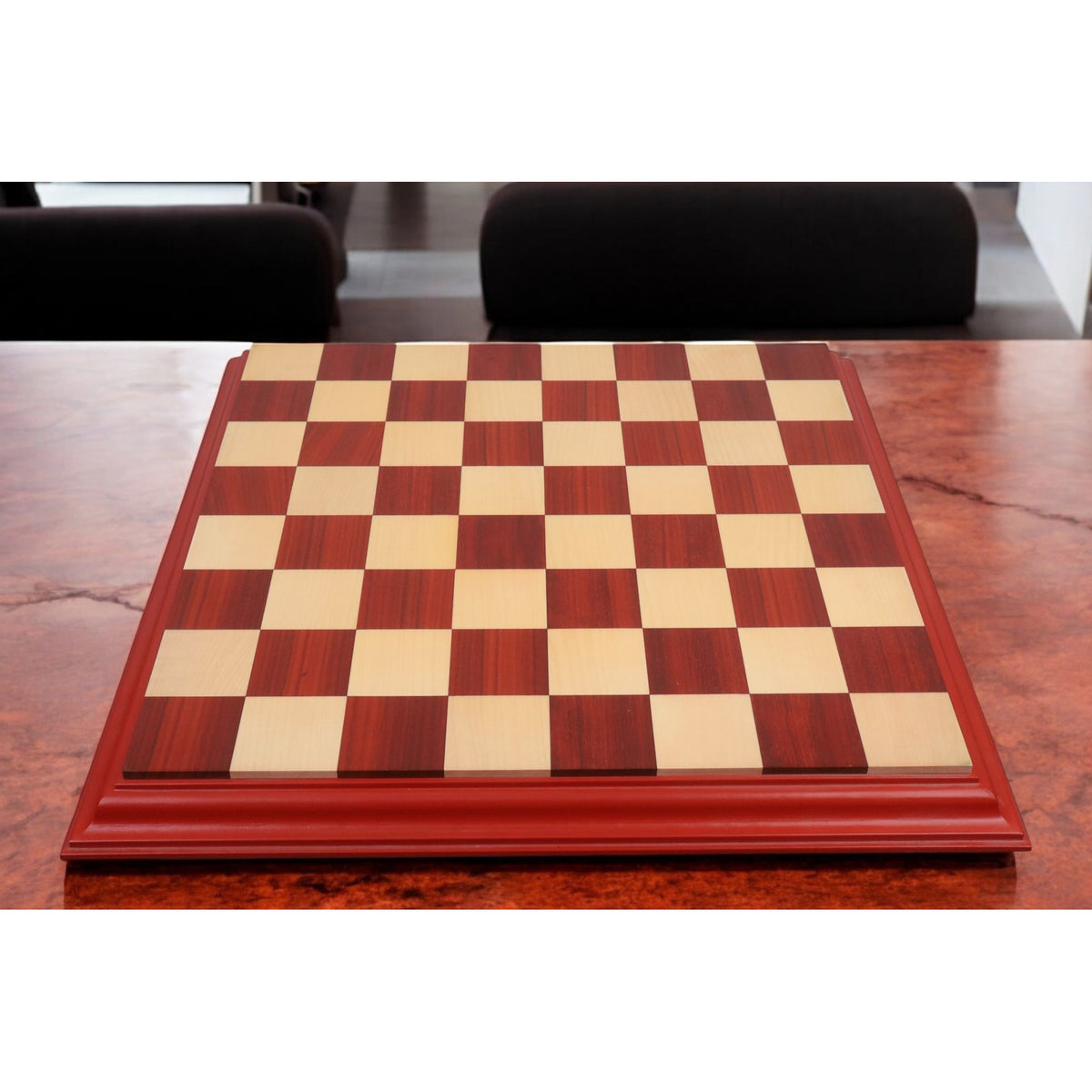 Large 23 inch professional wooden chessboard placed on a dark wood table in a luxury interior setting.