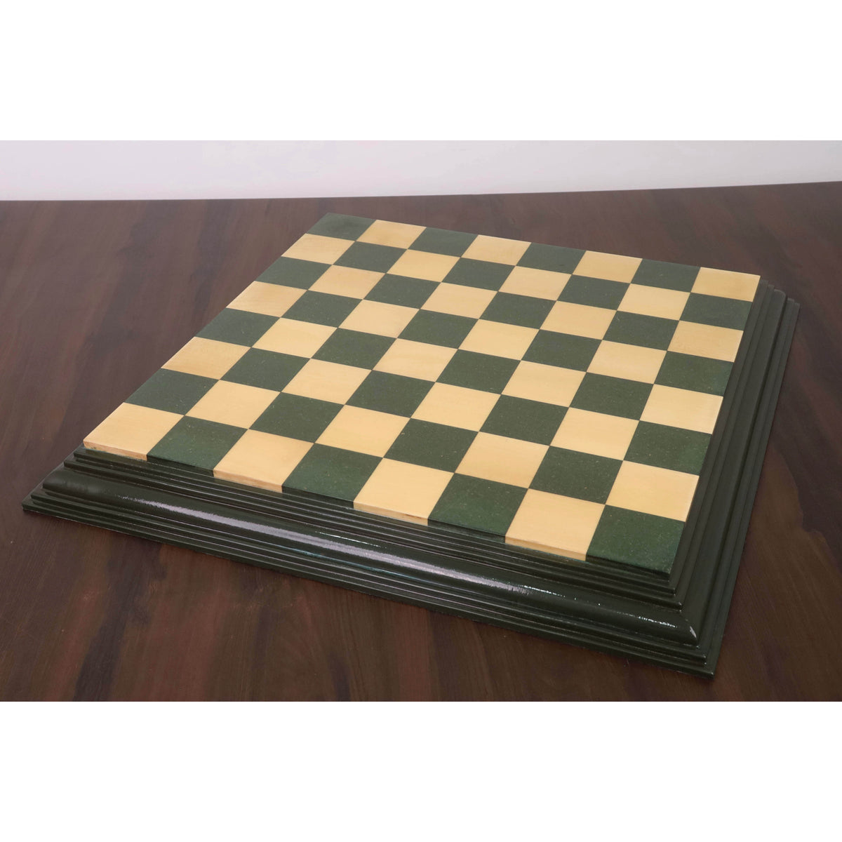 Full 21 inch green and maple wood chess board with decorative borders on a wooden table.
