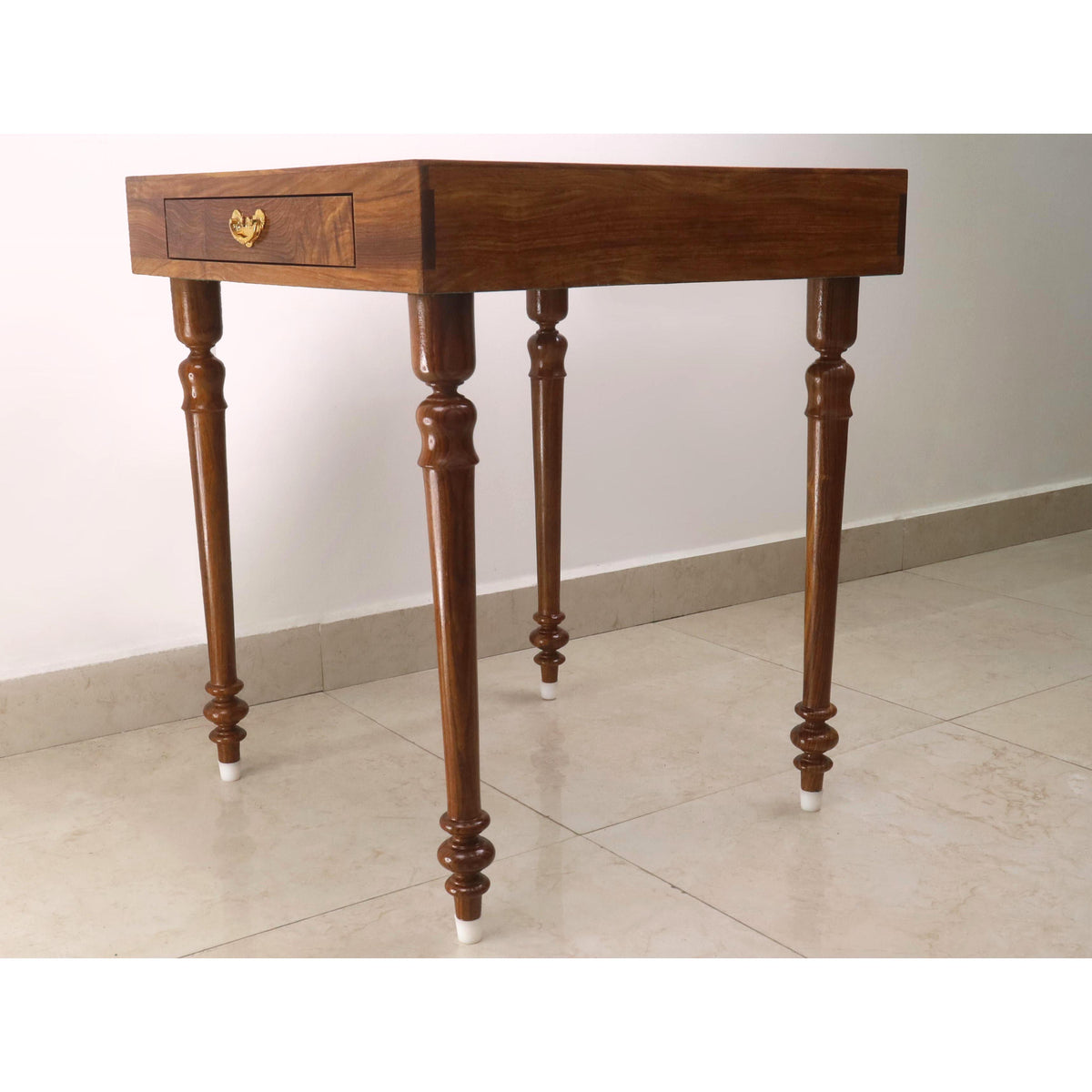 Profile view of a wooden chess table featuring elegantly lathed legs and a brass drawer handle.
