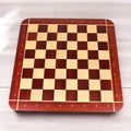 Full overhead perspective of a luxury 23" Bud Rosewood and Maple wooden chessboard on a light wood floor.
