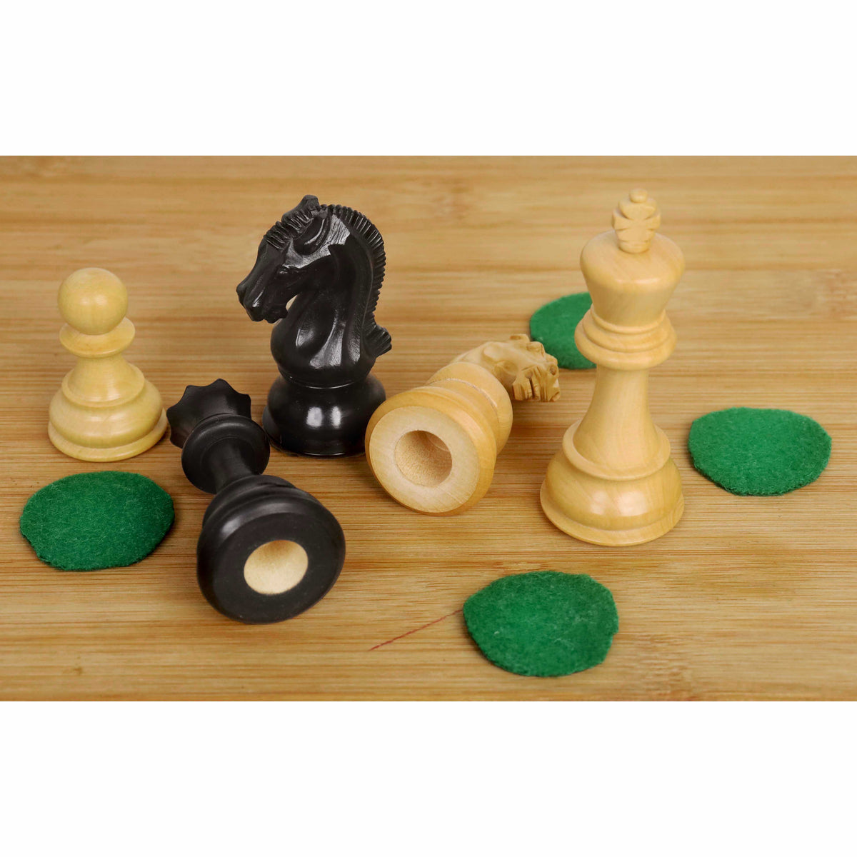 Ebonised and boxwood chess pieces with unattached green felt pads, showing the sensor-ready hollow base.