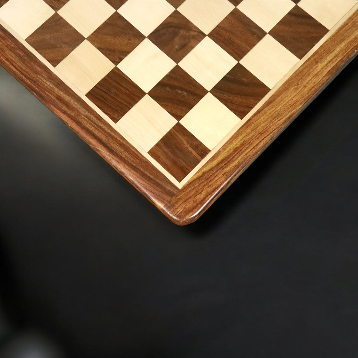 Top-down view of a handcrafted golden rosewood and maple chess board corner with a minimalist aesthetic.