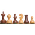 Six Staunton chess pieces in boxwood and acacia wood lined up on a wooden rail.
