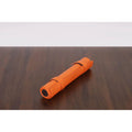 Compact, portable orange roll-up backgammon travel set secured for storage.