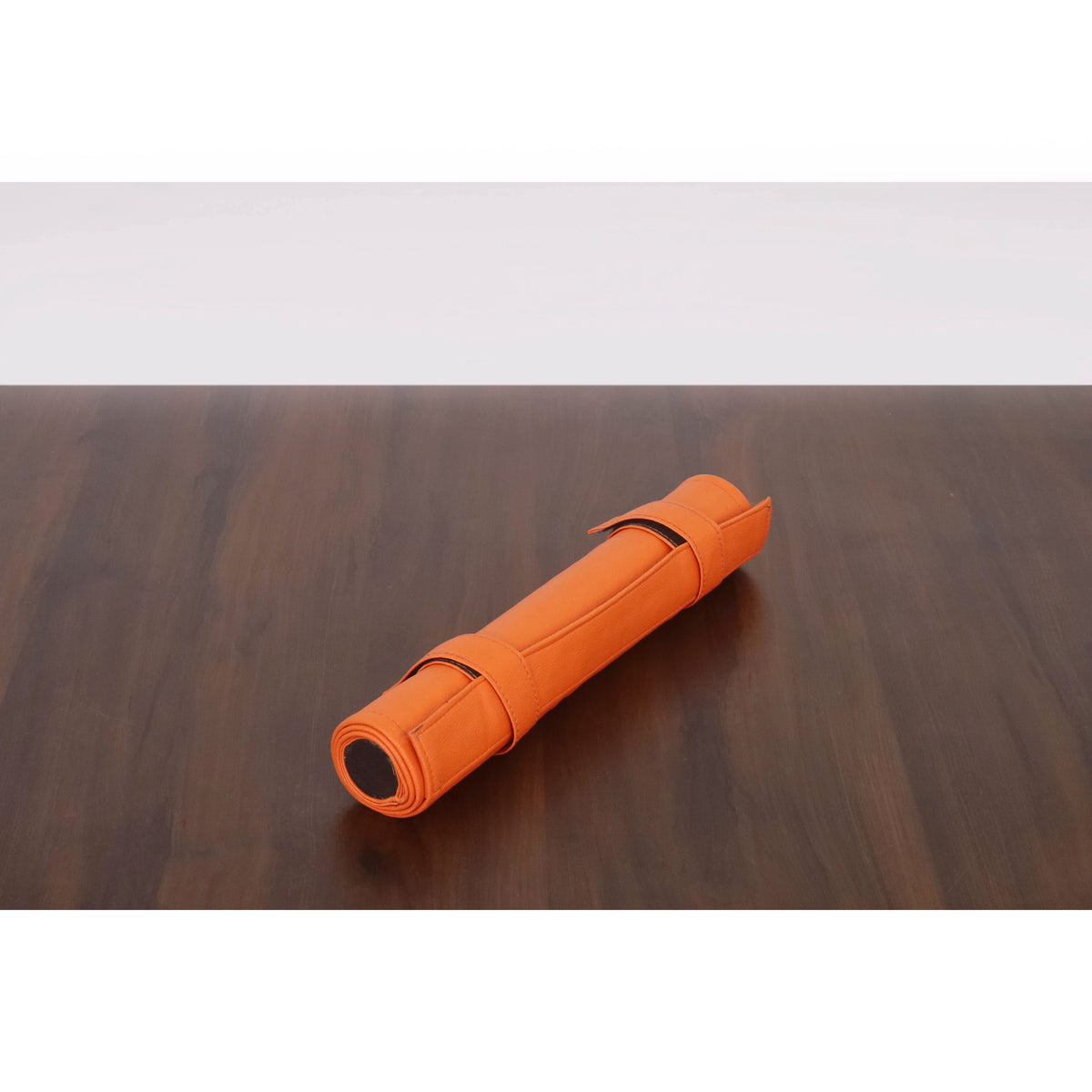 Compact, portable orange roll-up backgammon travel set secured for storage.