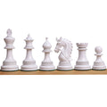 Lineup of white lacquered boxwood pieces from the luxury Napoleon Staunton chess set on a light wood surface.