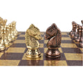 Two unique Staunton-inspired brass knights in copper and gold face off on the ornate metal chess board.