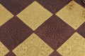 Close-up, overhead view of the detailed floral and geometric embossing on the metal chess board squares.