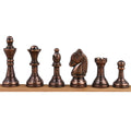 A lineup of the copper brass chess pieces (king, queen, bishop, knight, rook, pawn) on a wooden display.