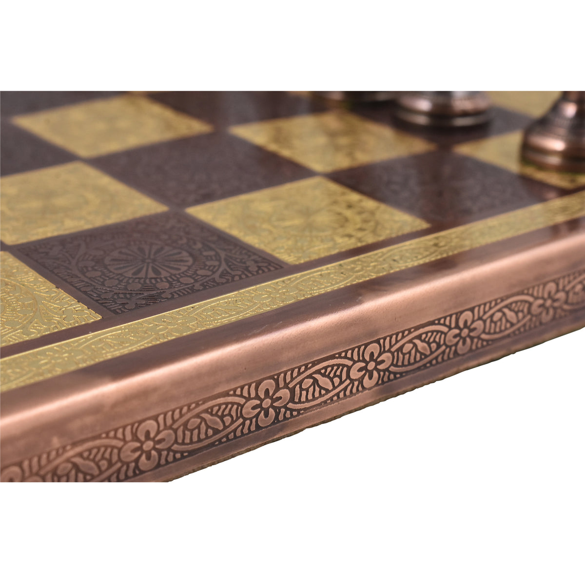 Close-up of the ornate, embossed floral pattern on the edge of the copper and gold metal chess board.
